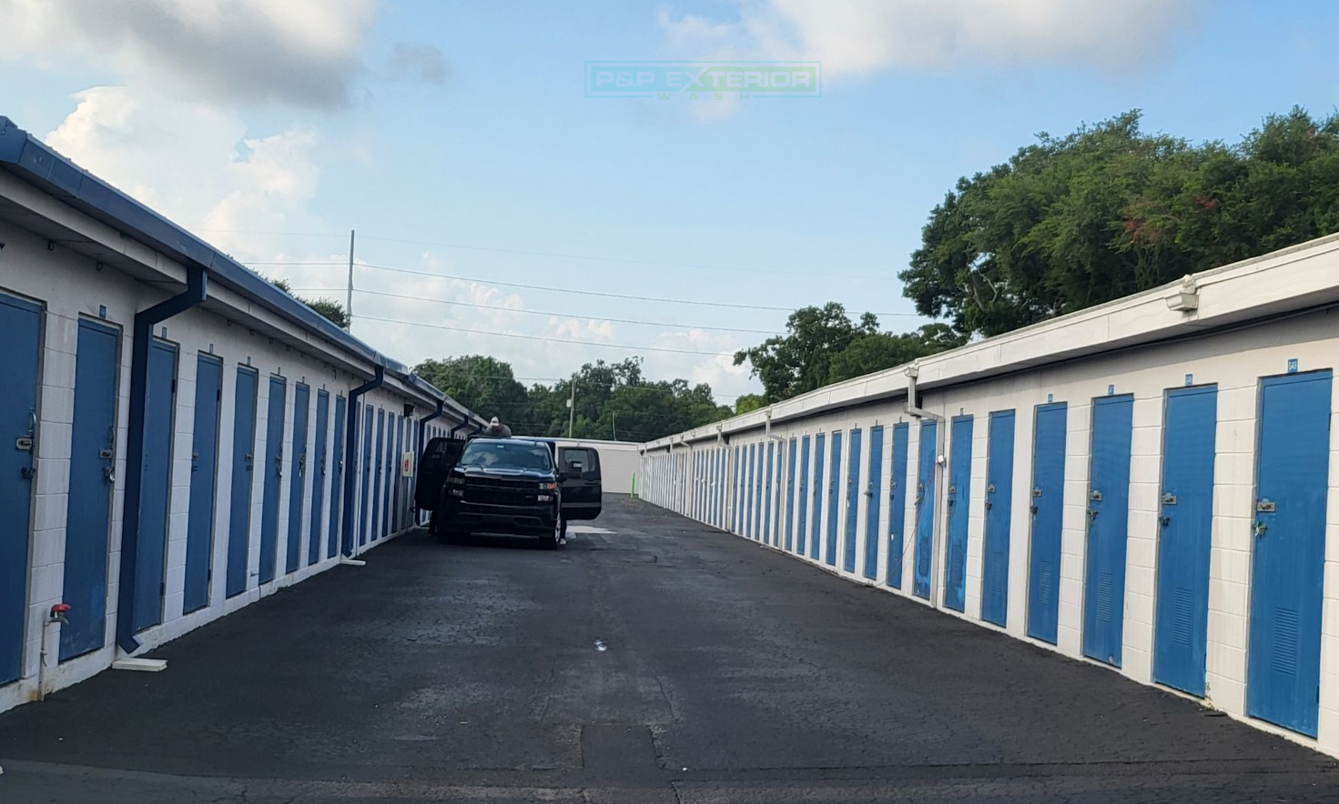 A row of blue and white striped buildings with cars parked in front of them.