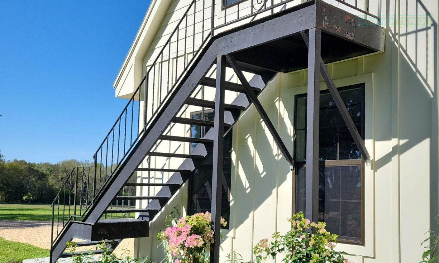 A white house with stairs leading up to the second floor
