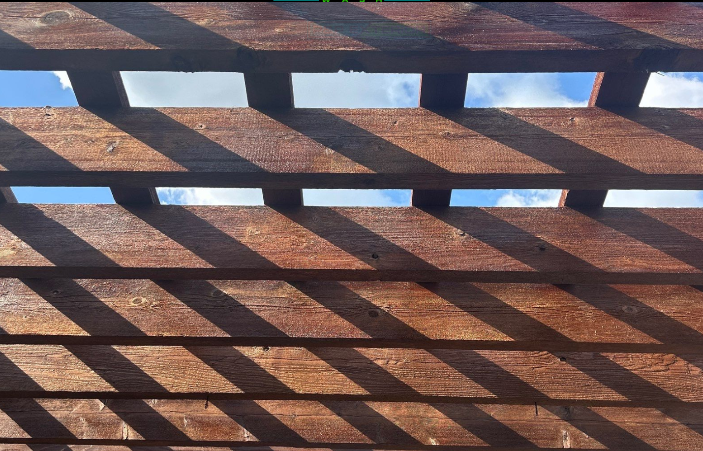 A wooden pergola with a blue sky in the background