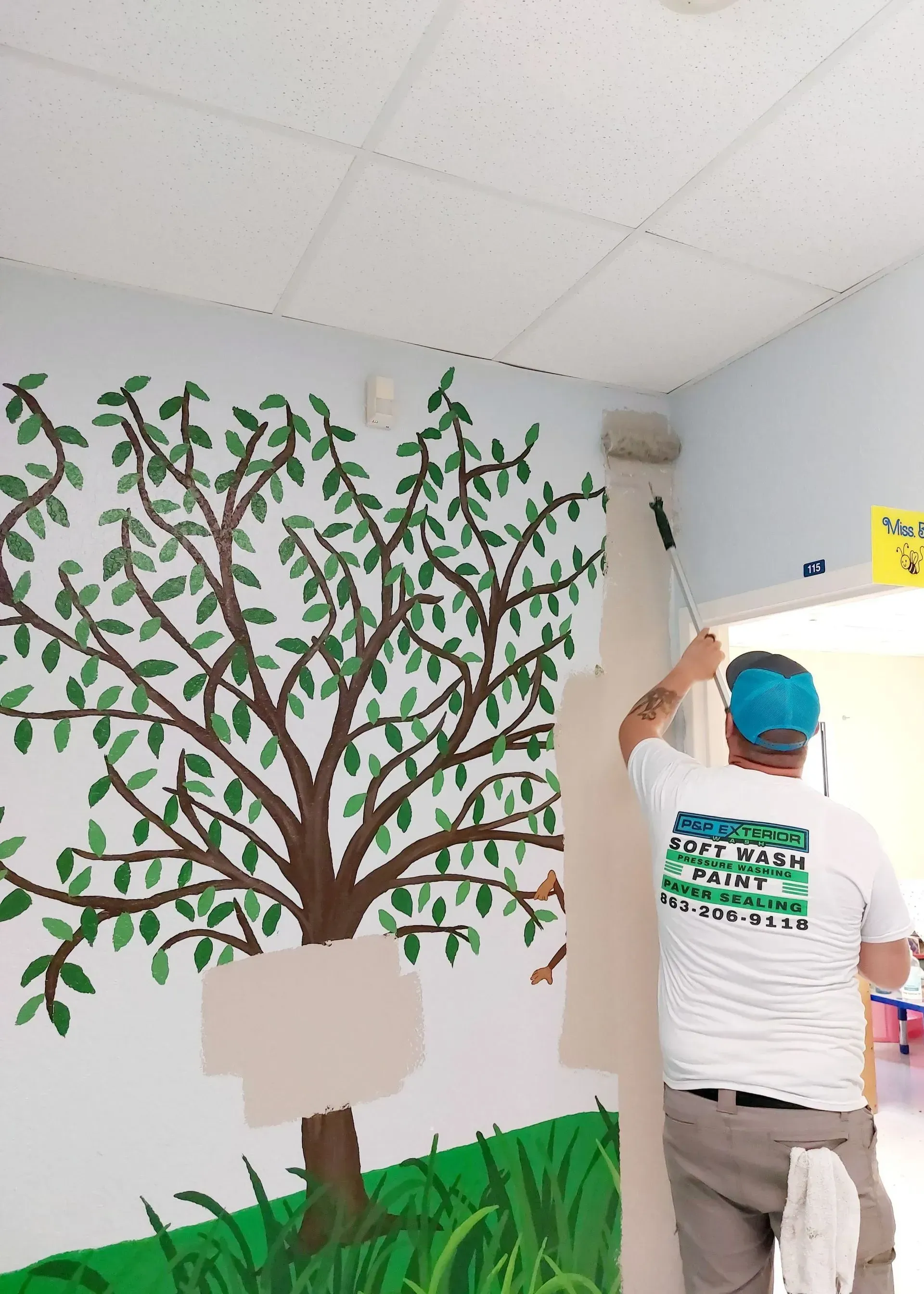 A man is painting a tree on a wall