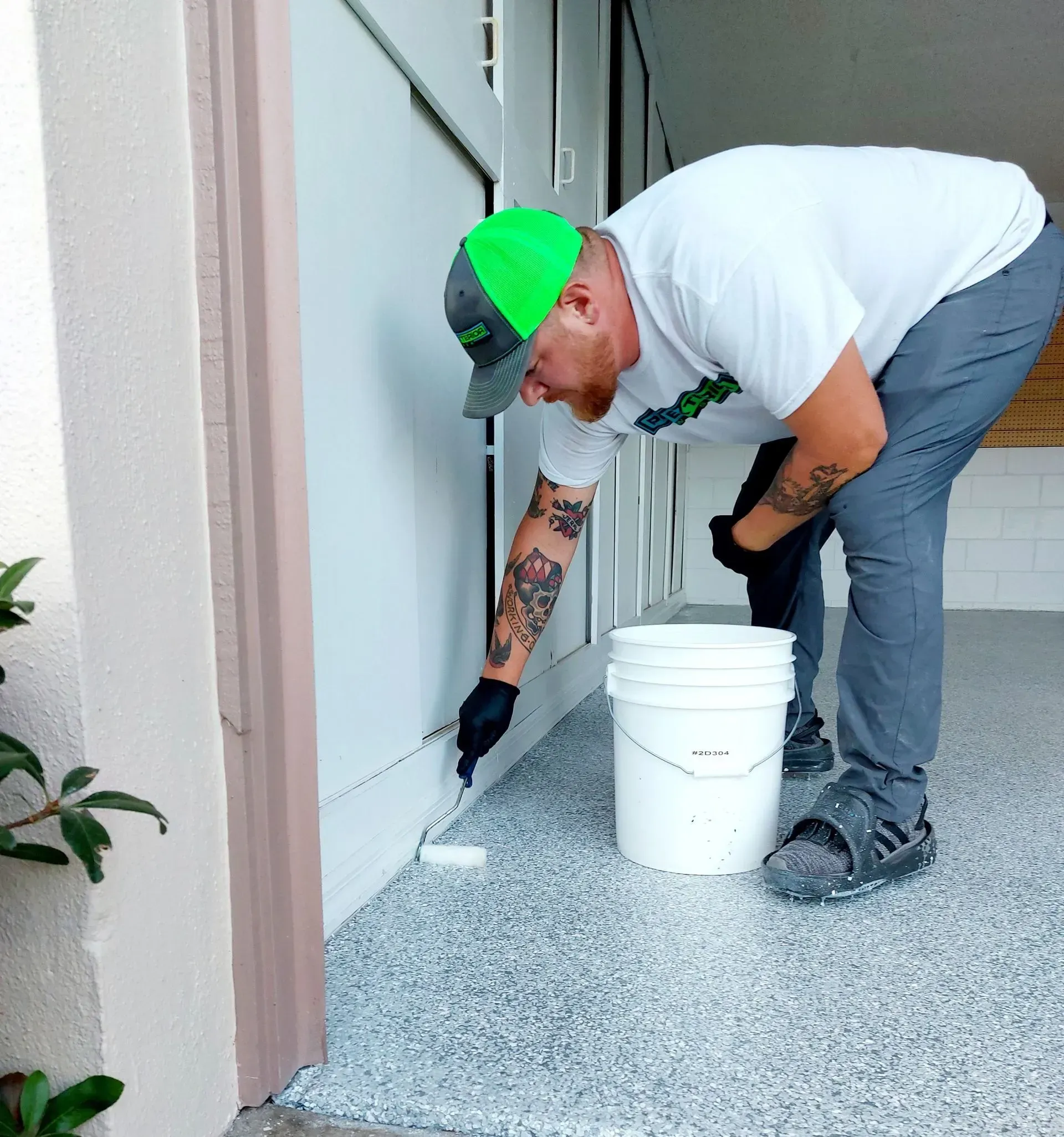 A man wearing a green hat is painting a wall