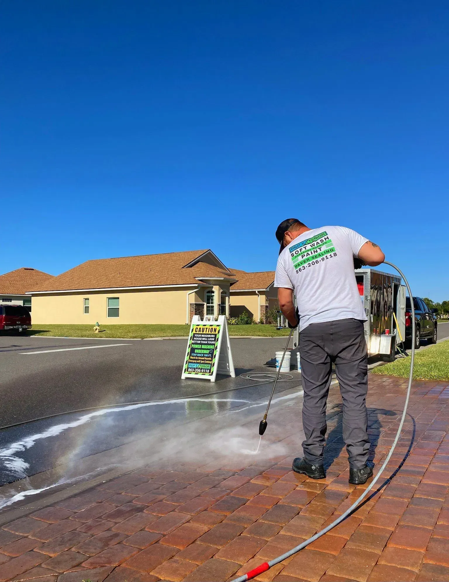 A man is cleaning a brick driveway with a high pressure washer.