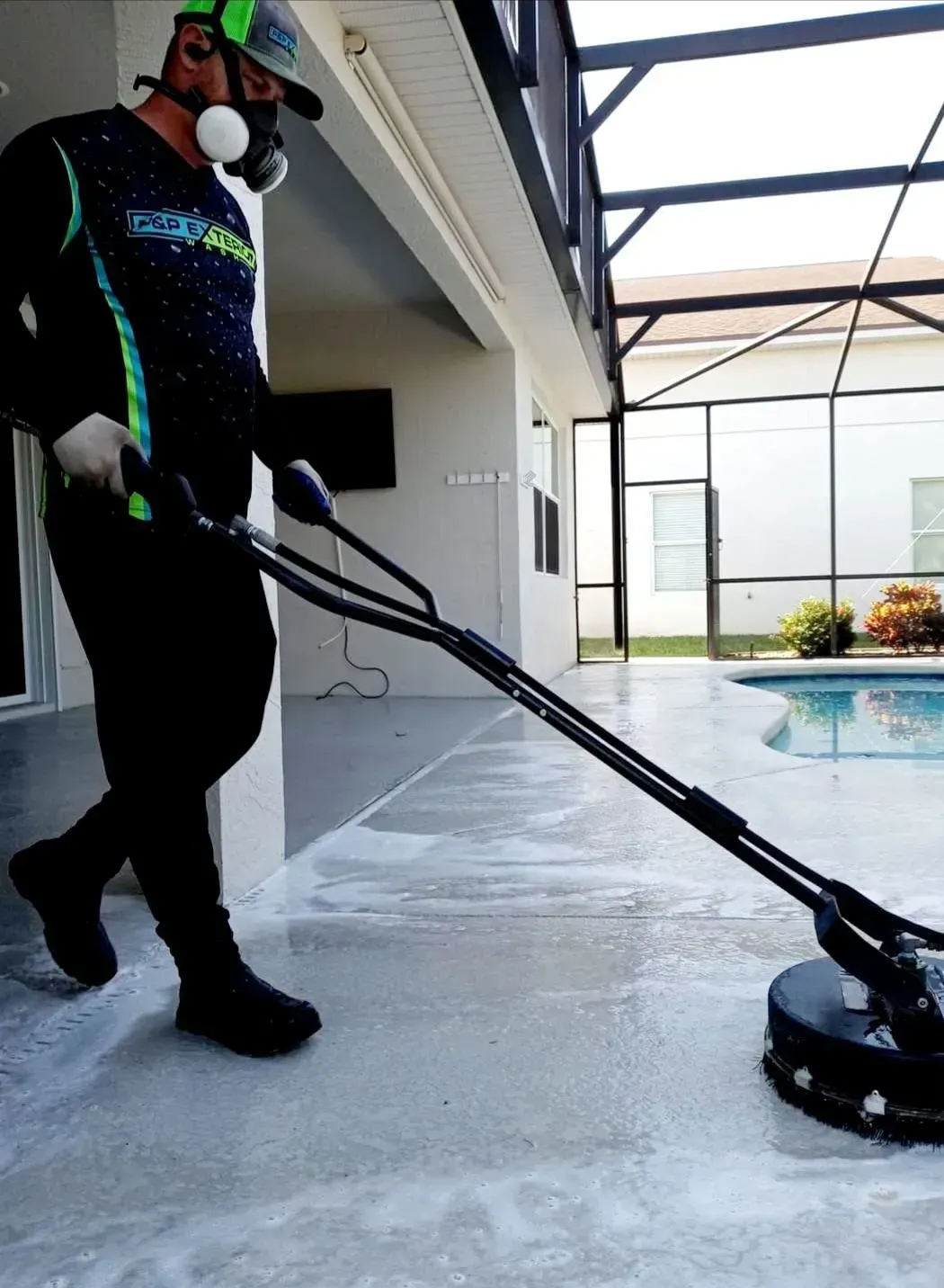 A man wearing a mask is using a machine to clean a pool deck.