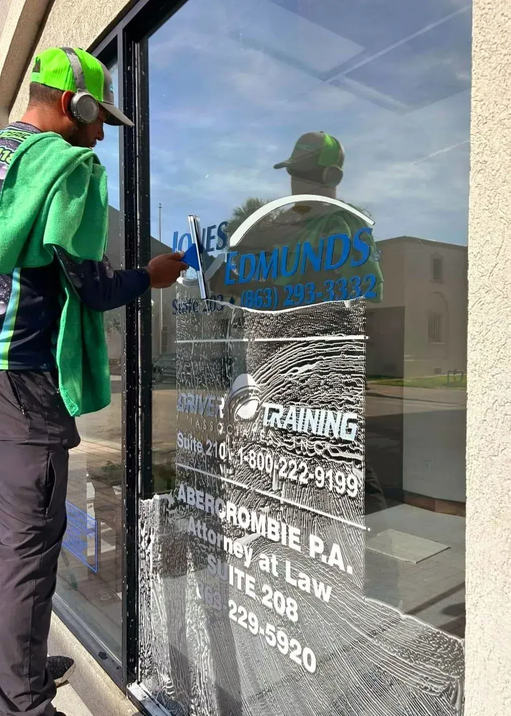 A man is cleaning a glass door of a building.