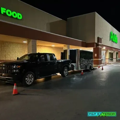 A black truck is parked in front of a food store