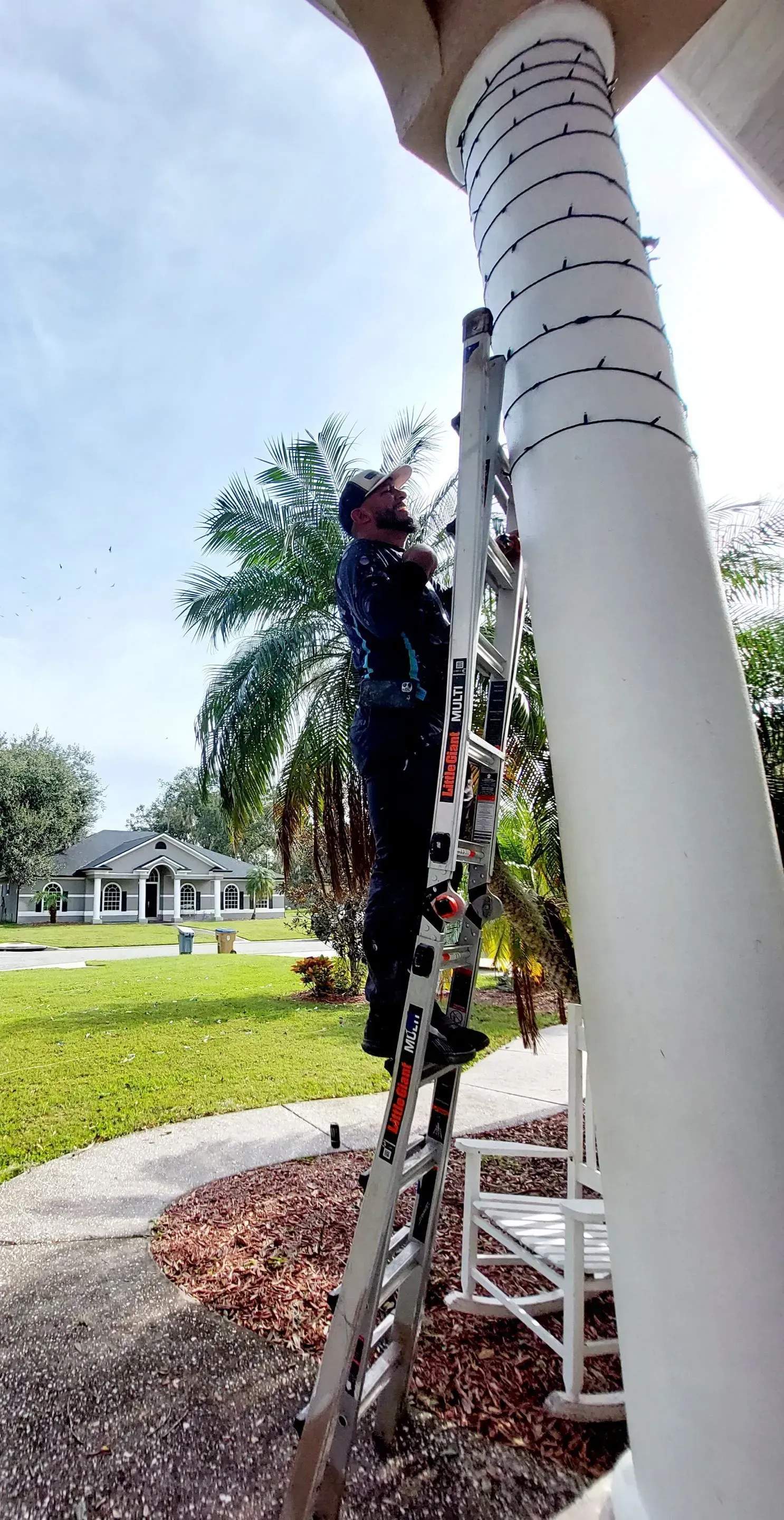A man is standing on a ladder on a porch.