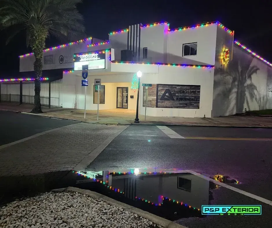 A white building is decorated with christmas lights at night.