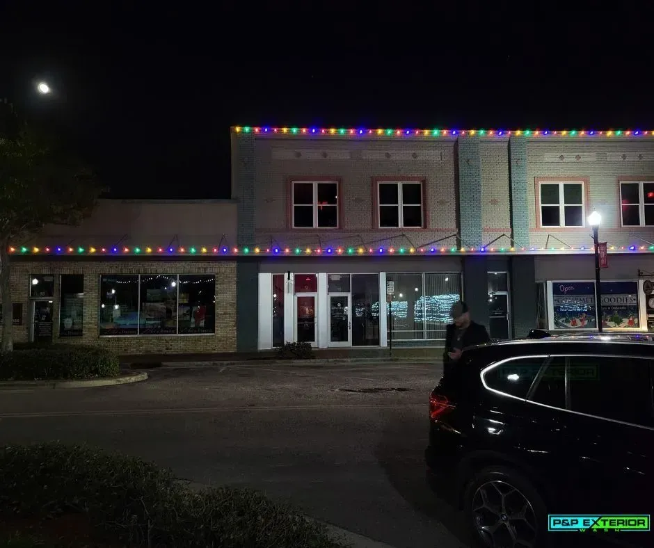 A car is parked in front of a building with christmas lights on it.