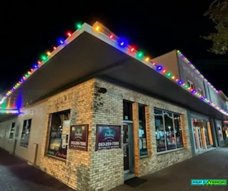 A brick building with christmas lights on it is lit up at night.