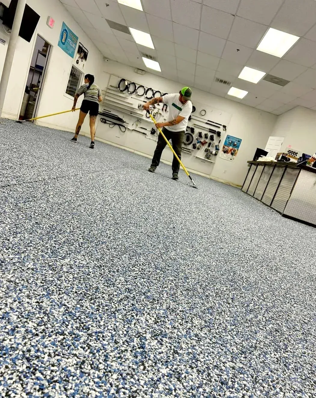 A man and a woman are standing on a carpeted floor in a room.
