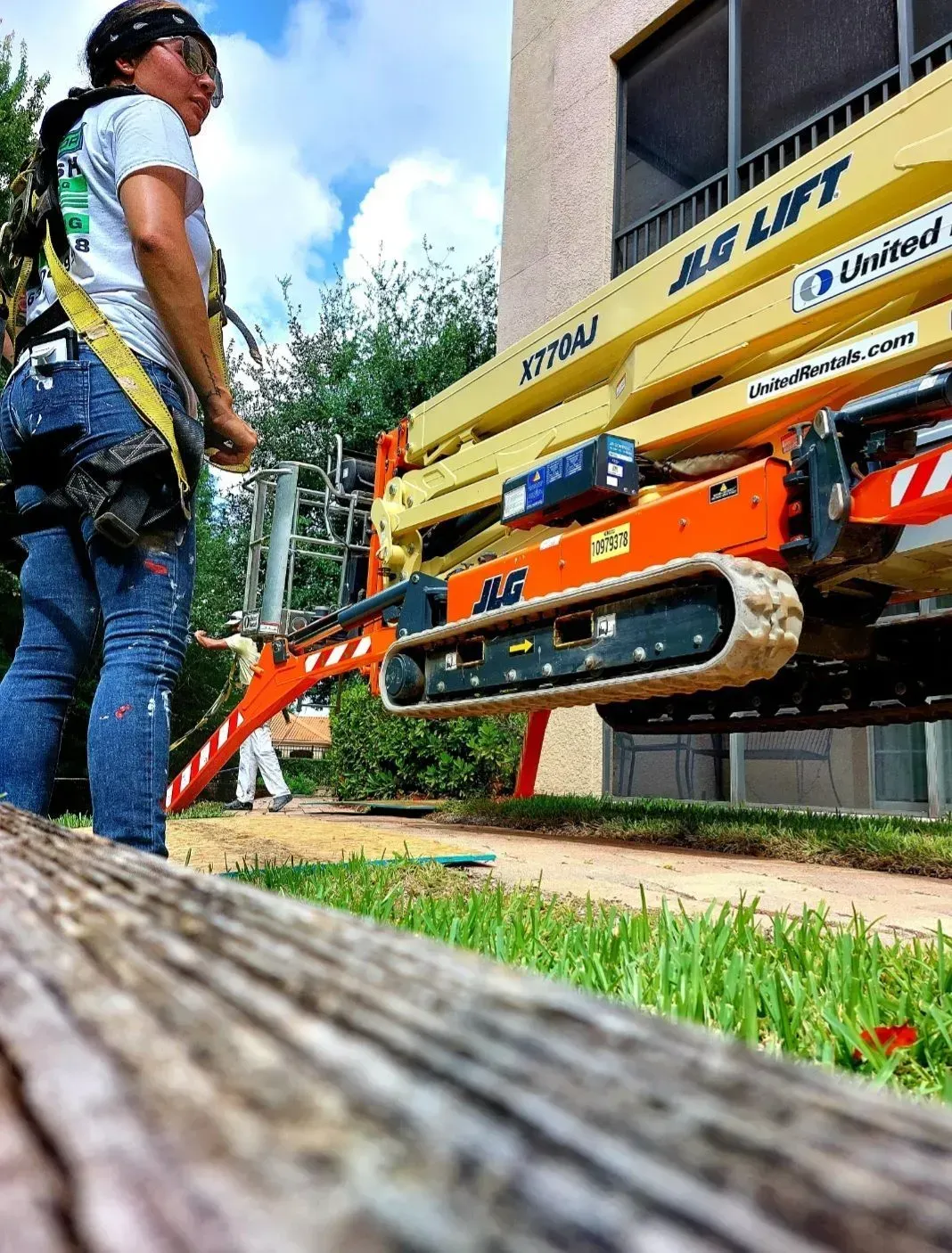 A woman is standing in front of a jlg lift.