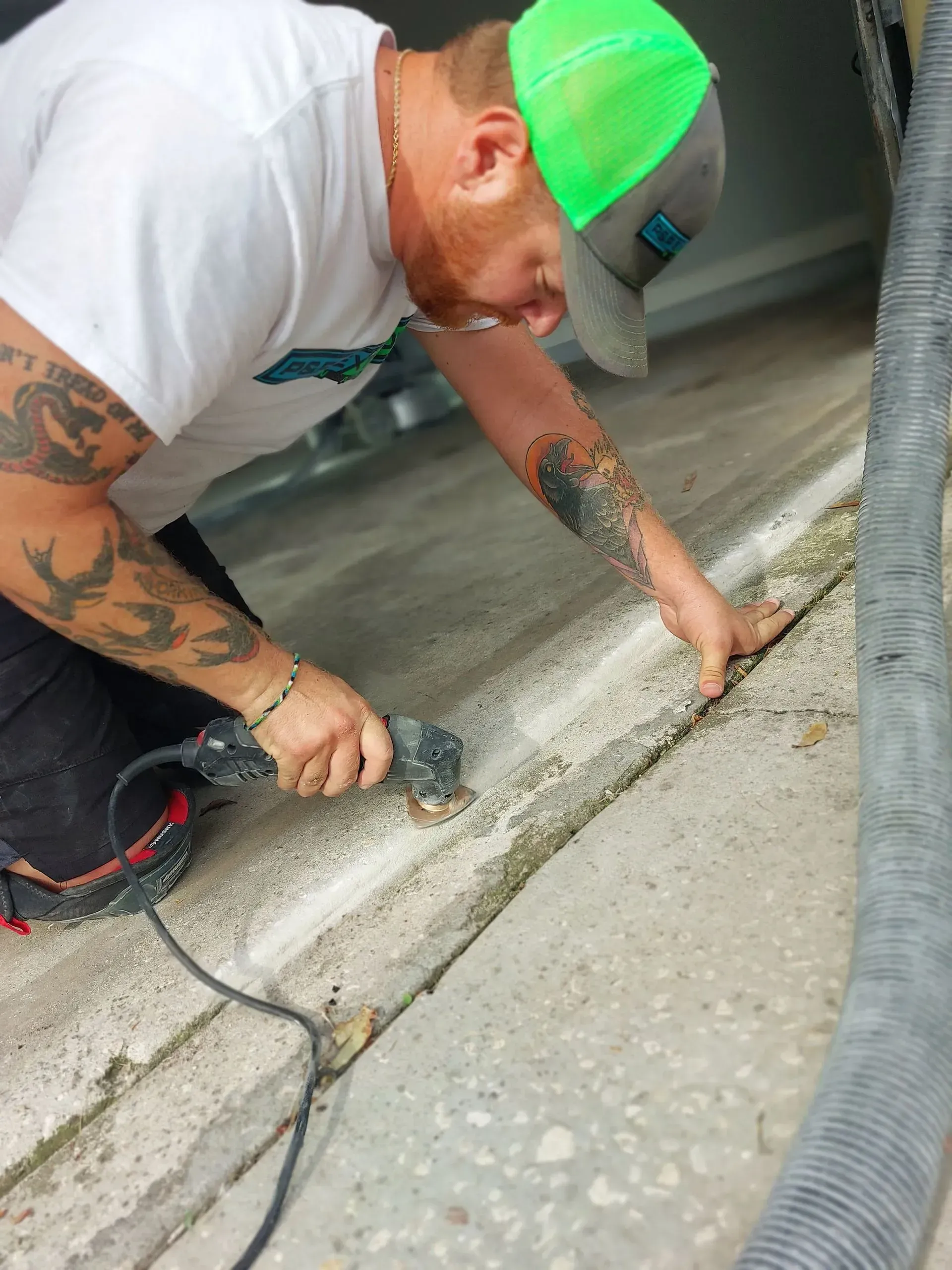 A man is kneeling down using a machine to cut concrete.