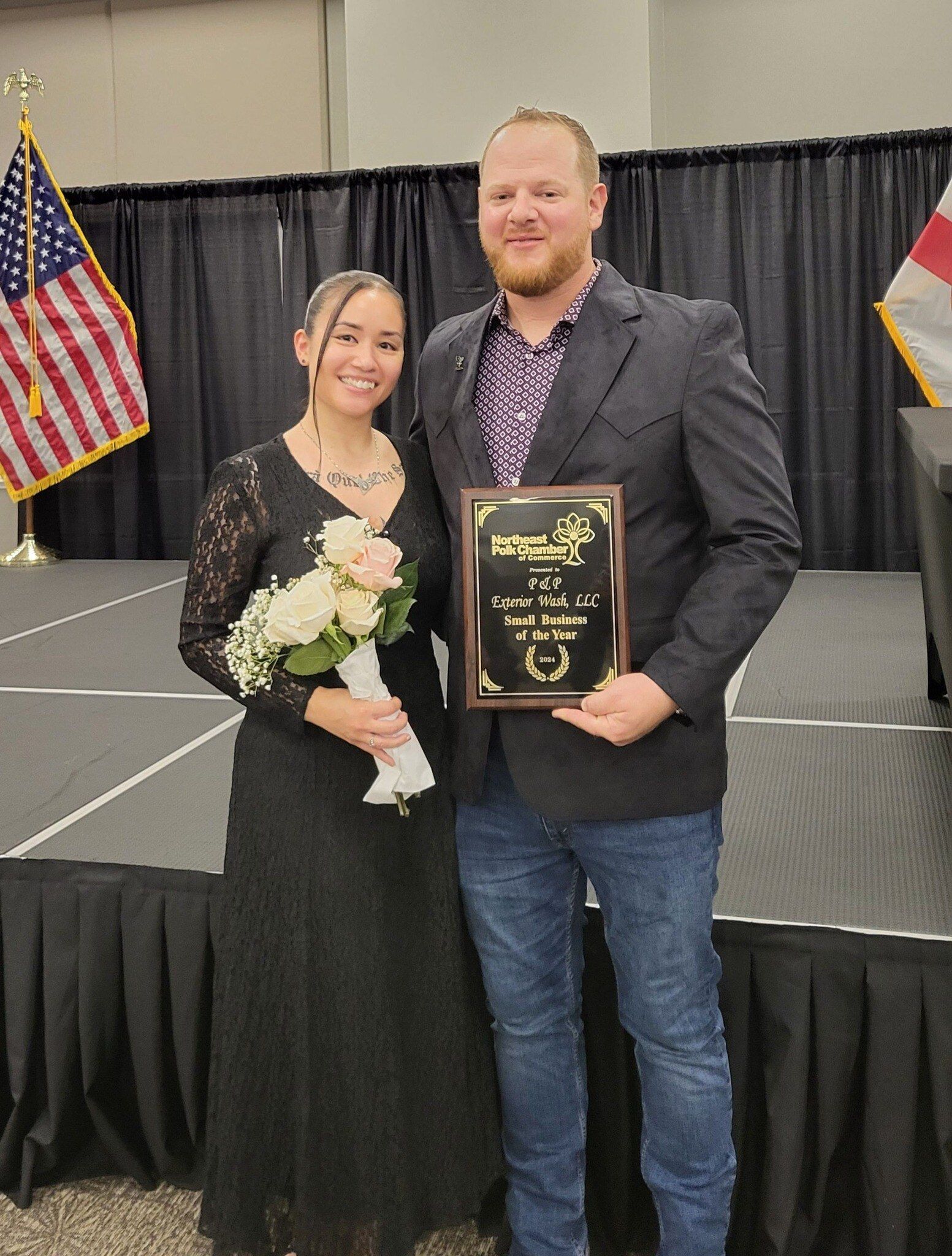 A man and a woman are standing on a stage holding a plaque.