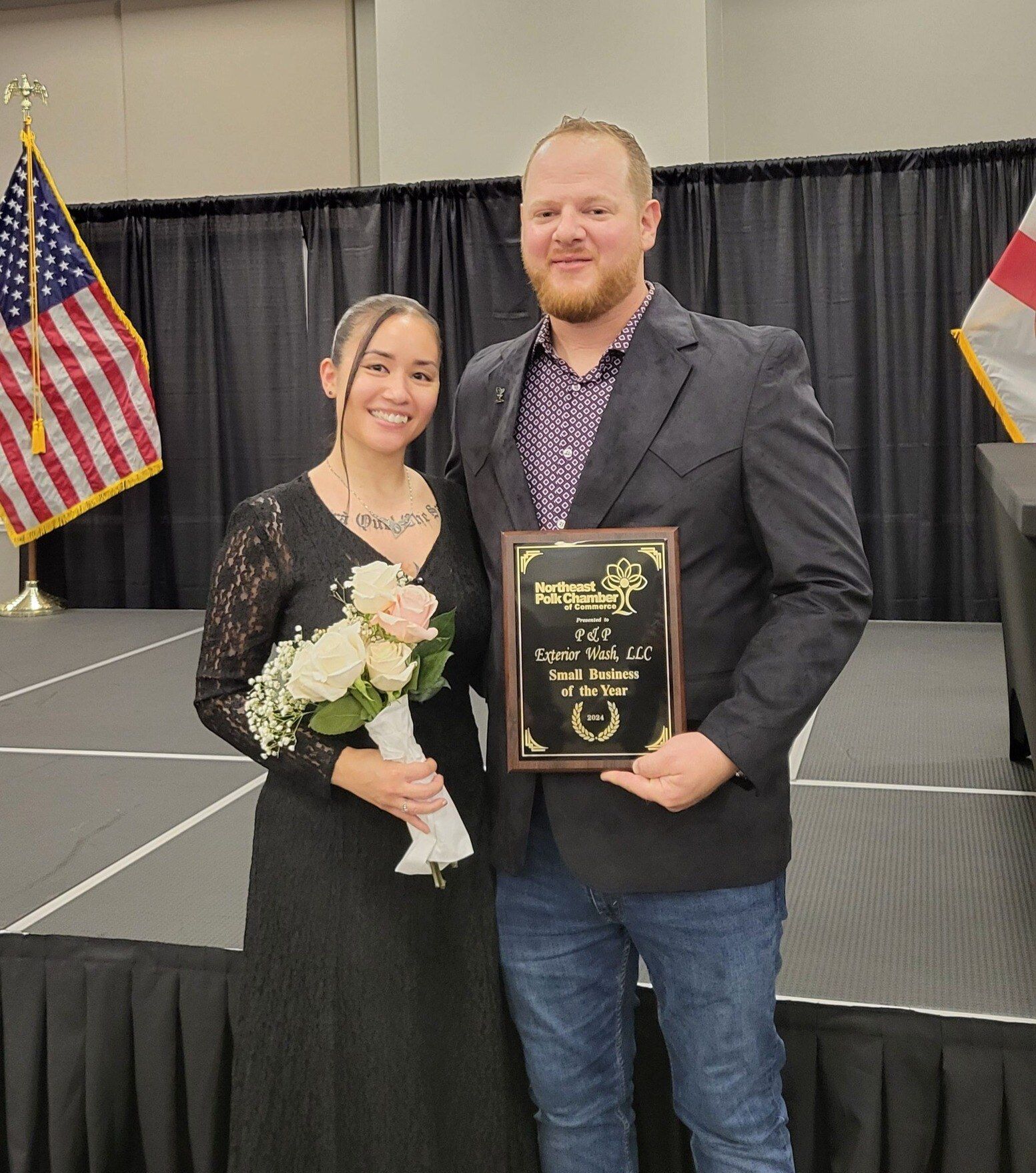 A man and a woman are standing on a stage holding a plaque.