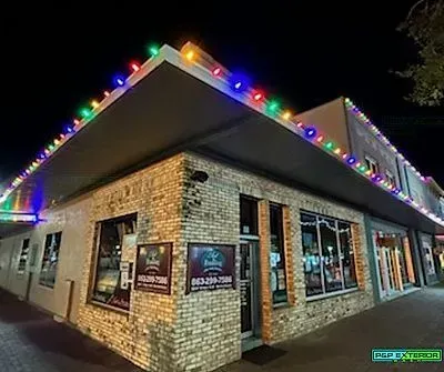 A brick building with christmas lights on the roof at night.