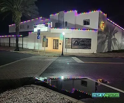 A white building with christmas lights on it is lit up at night.
