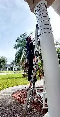 A man is standing on a ladder attached to a pole.