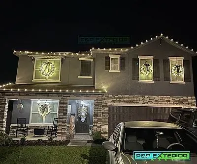 A house is decorated with christmas lights and a car is parked in front of it.