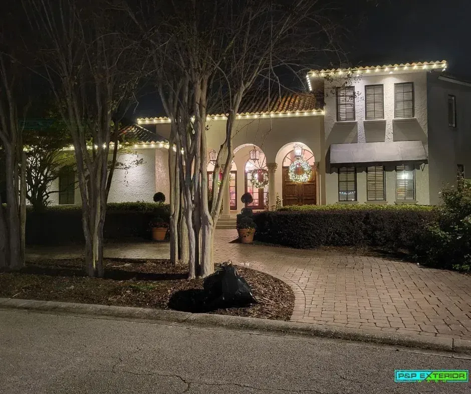 A large house with christmas lights on it is lit up at night.