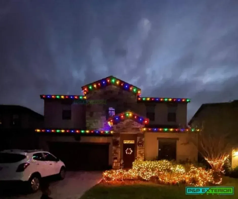 A house is decorated with christmas lights and a car is parked in front of it.