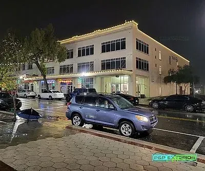 A blue suv is parked in front of a building at night.
