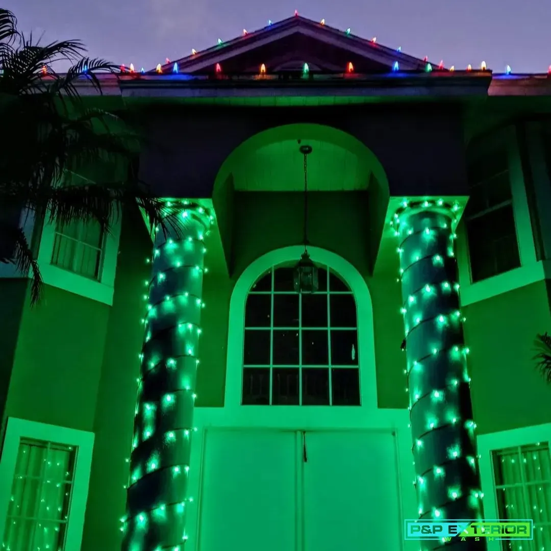 The front of a house is lit up with green christmas lights