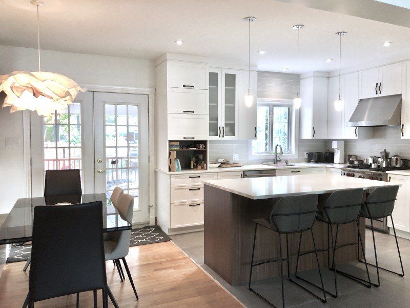 Cuisine moderne avec armoires blanches, îlot et table à manger.