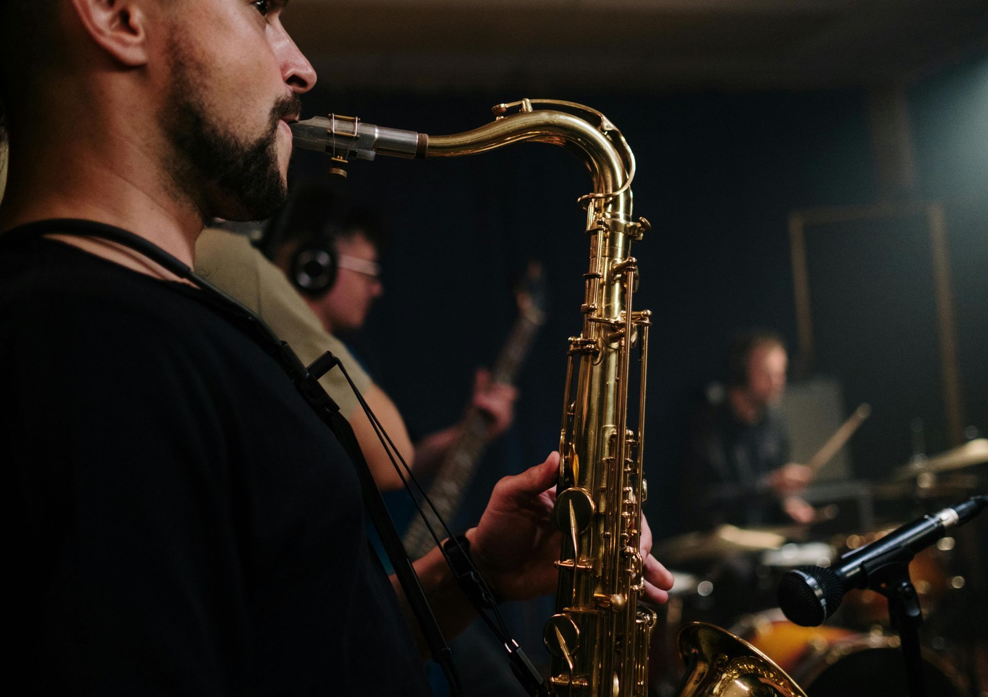 A man is playing a saxophone in front of a microphone.