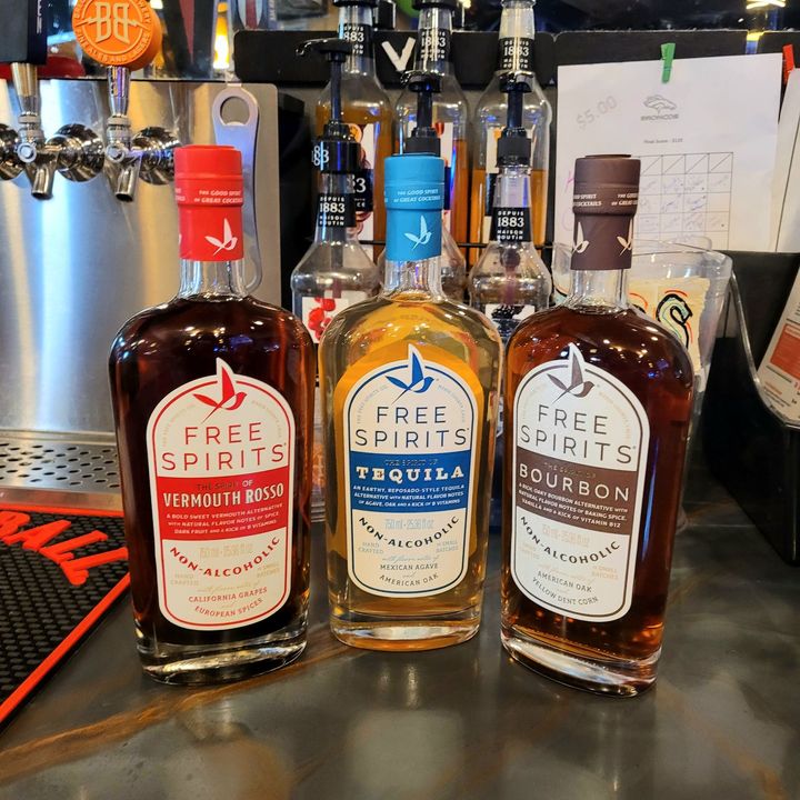 Three Free Spirits bottles on a bar counter: aperitif, tequila, and bourbon.