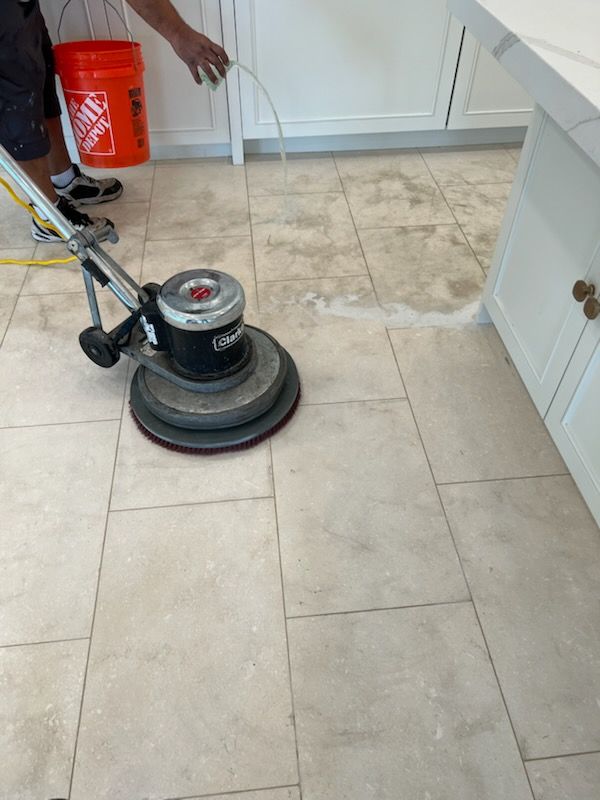 Floor being cleaned with a rotary machine in a kitchen. The floor is light-colored tile.