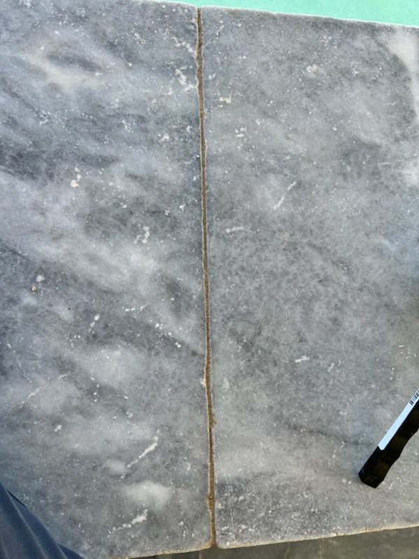 Two gray marble slabs with a thin, light-colored grout line between them.