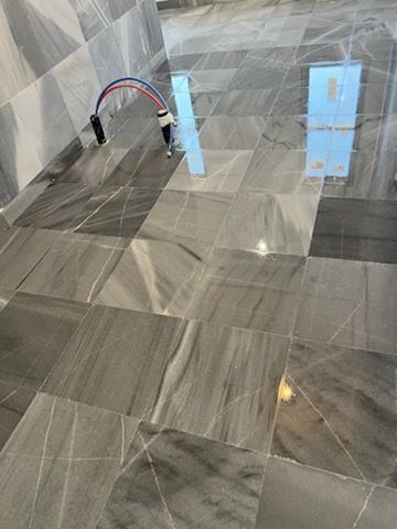 Gray and white marble tiled floor with electrical cables and a reflective object.