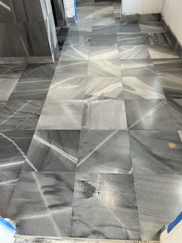 Gray and white marble tiled floor in a hallway, with veining patterns.