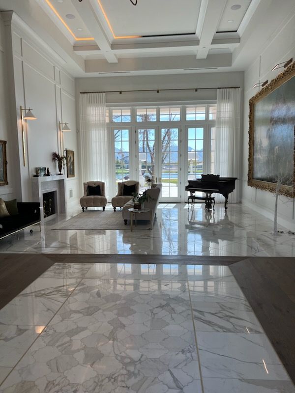 Elegant living room with marble floors, grand piano, and large windows.