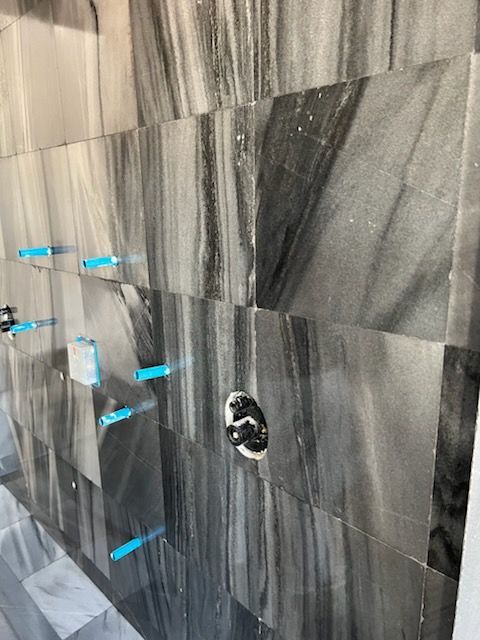 Gray marble shower wall with water fixtures.
