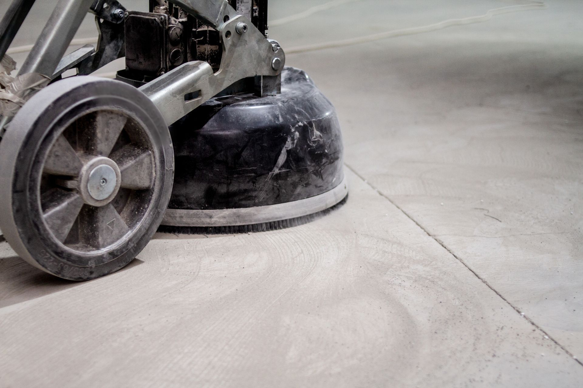 Floor grinder smoothing a concrete floor, creating a fine dust.
