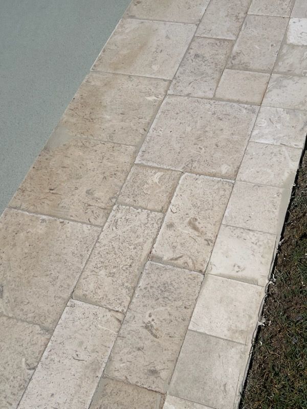 Stone patio tiles next to a light gray surface and grass.