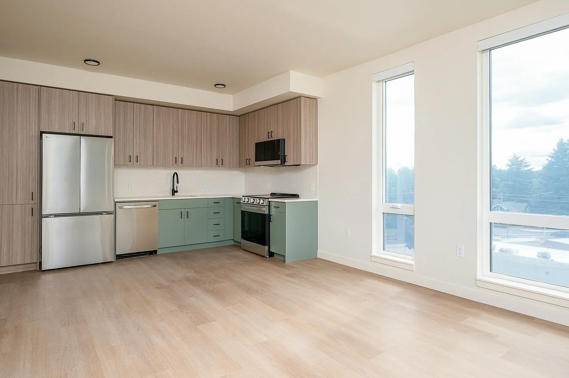 Modern kitchen with stainless steel appliances, light wood cabinetry, and mint green lower cabinets.