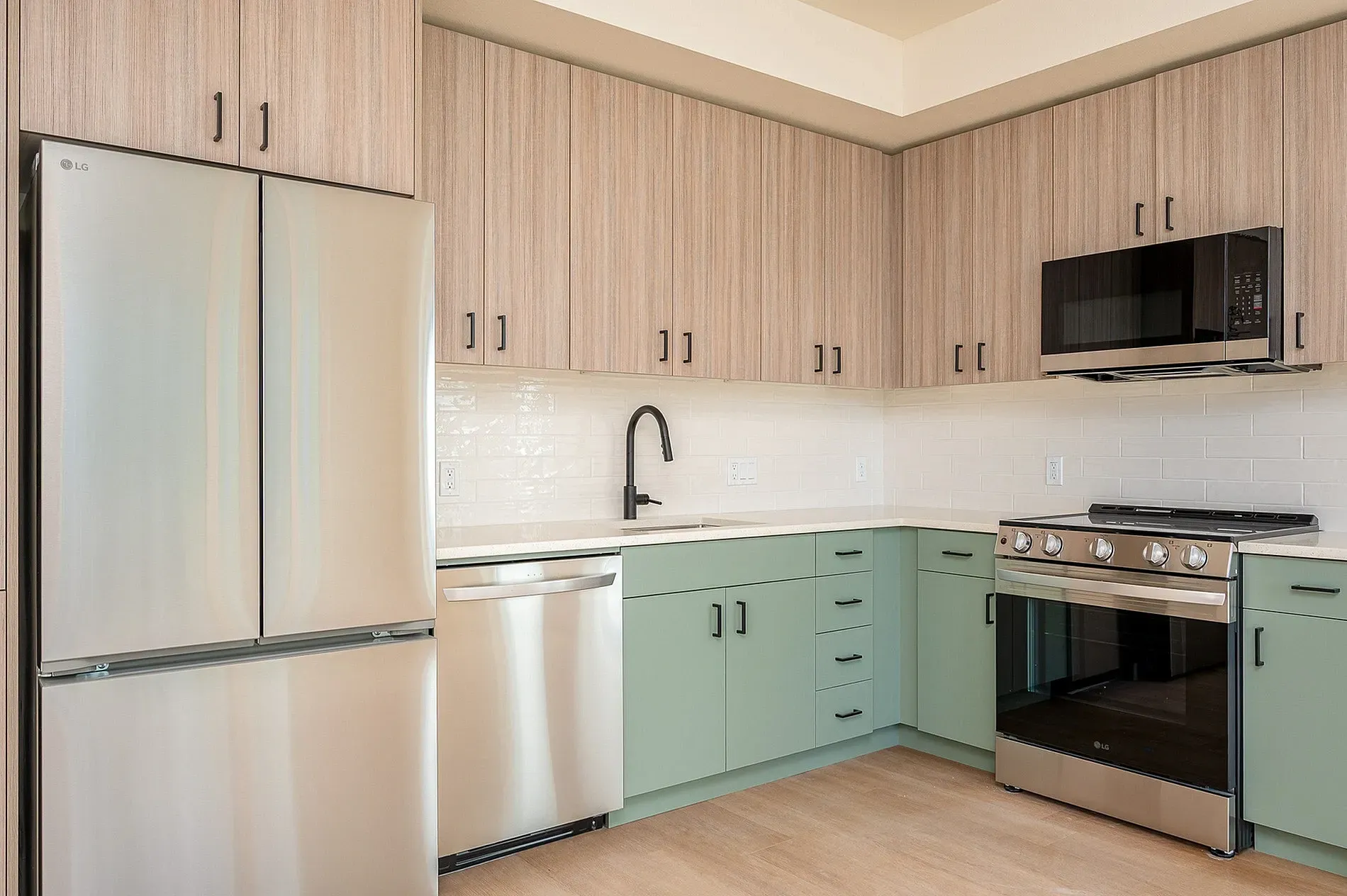 Stainless steel appliances and dual-tone cabinets in a modern kitchen.