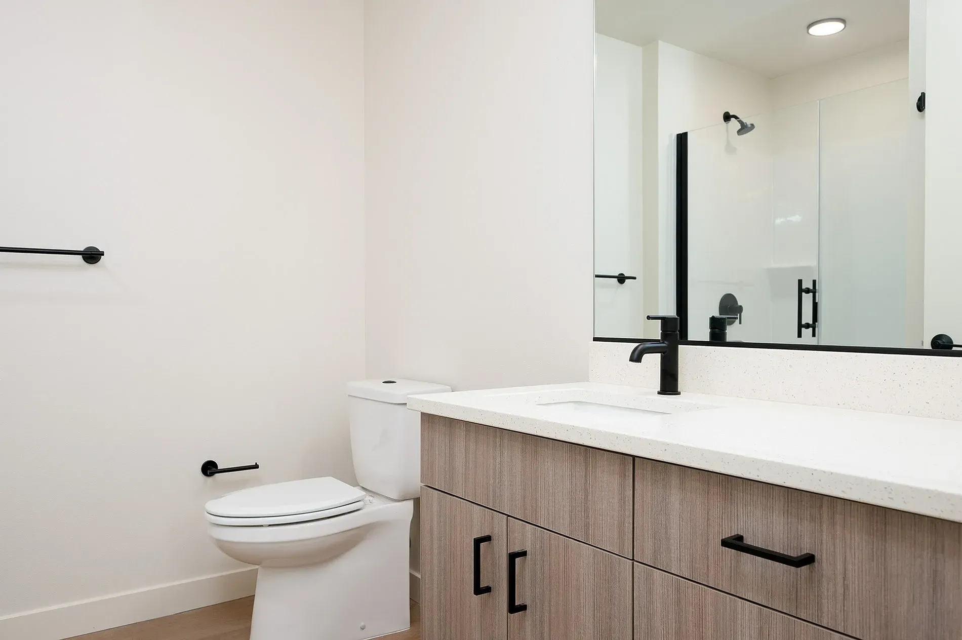 Modern bathroom with a sleek vanity, black faucet, and a glass-enclosed shower.