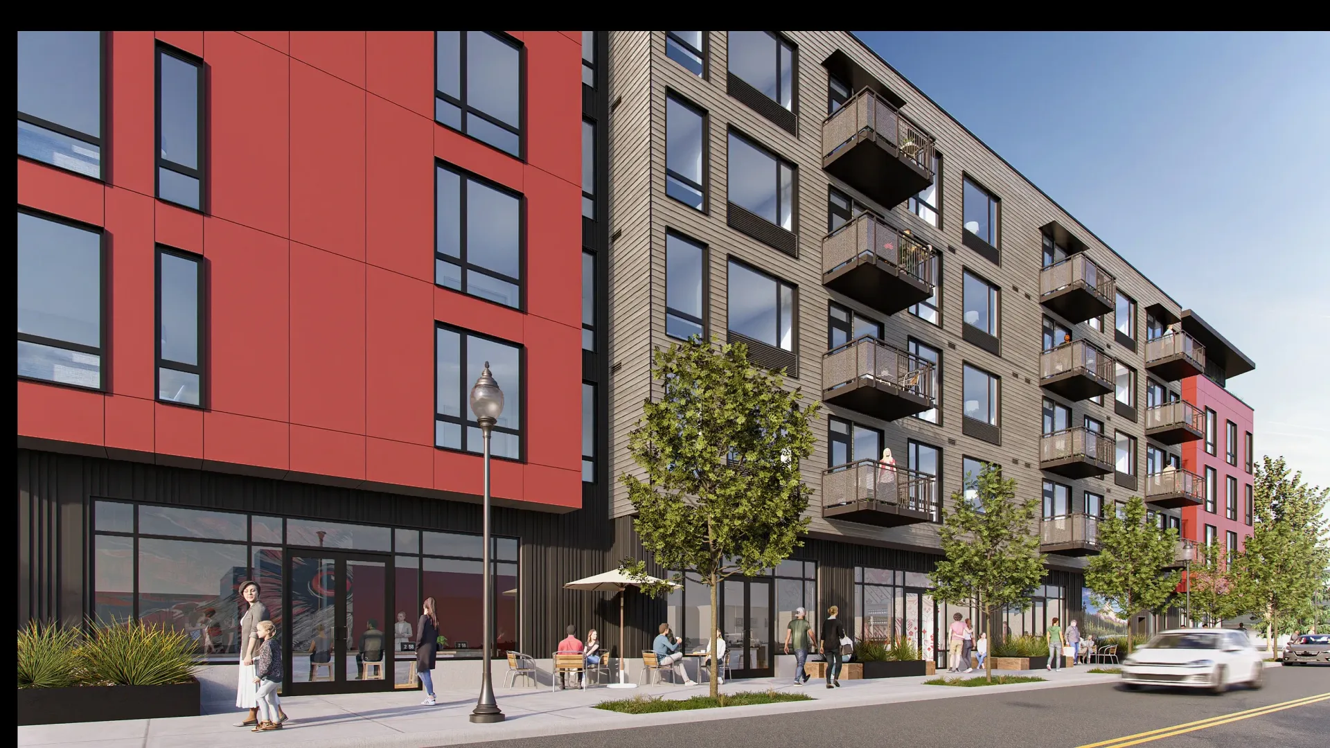 Modern apartment building exterior with red and gray panels, balconies, street-level storefronts, and pedestrians.