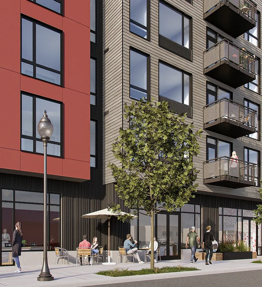 Exterior view of a modern apartment building with red and grey facades, balconies, and a street-level cafe with outdoor seating.