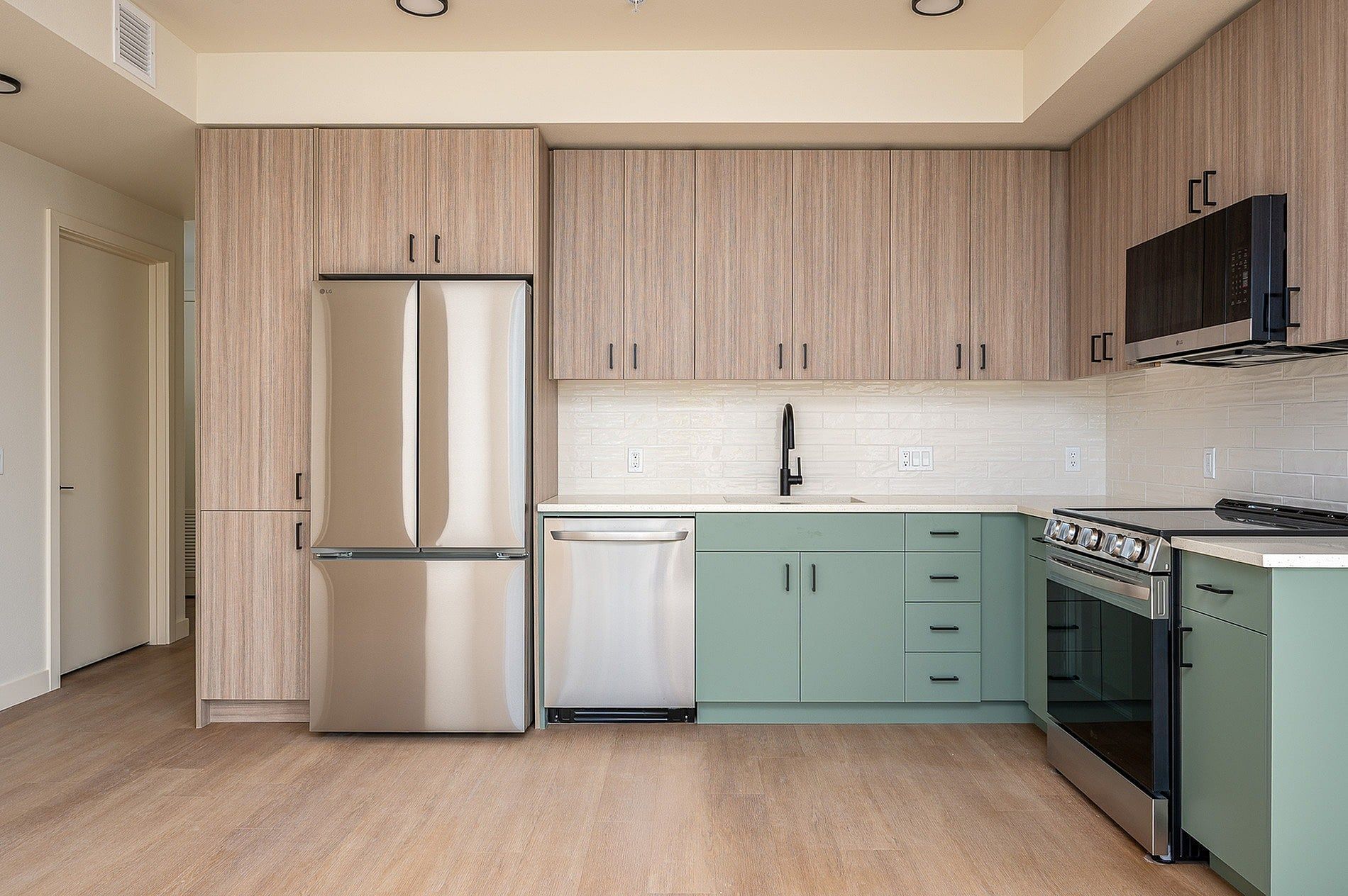 Modern kitchen with stainless steel appliances, light wood cabinets, and mint green lower cabinets.