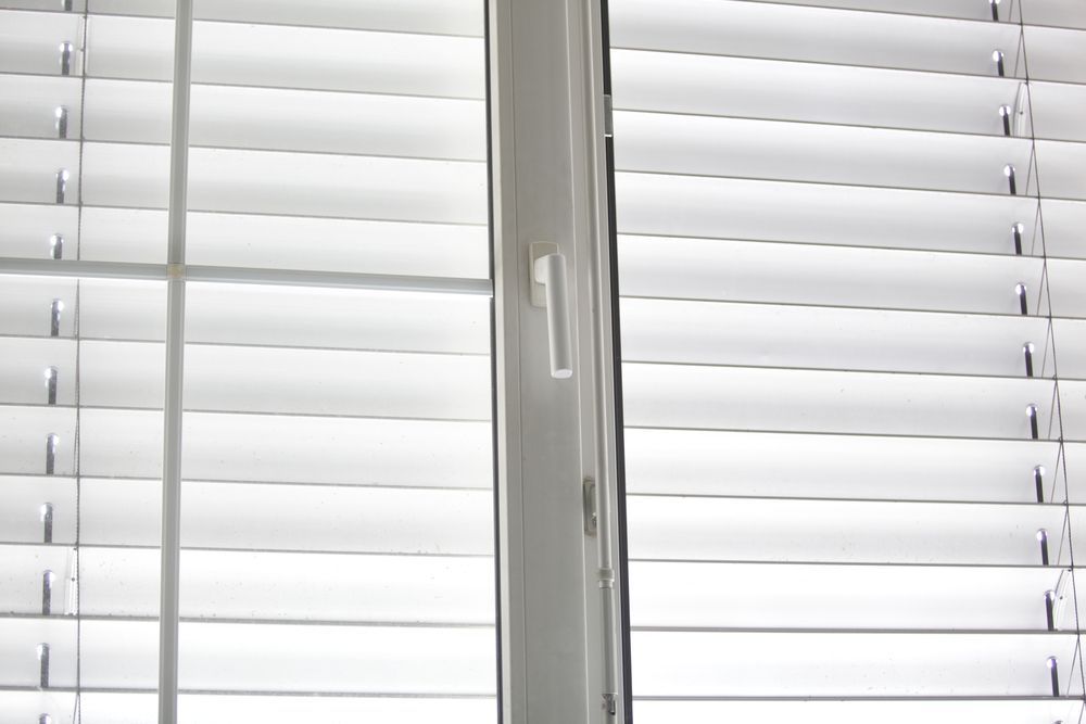 A Close Up of a Window With White Blinds on It — Catrina's Custom Curtains & Blinds in Toukley, NSW
