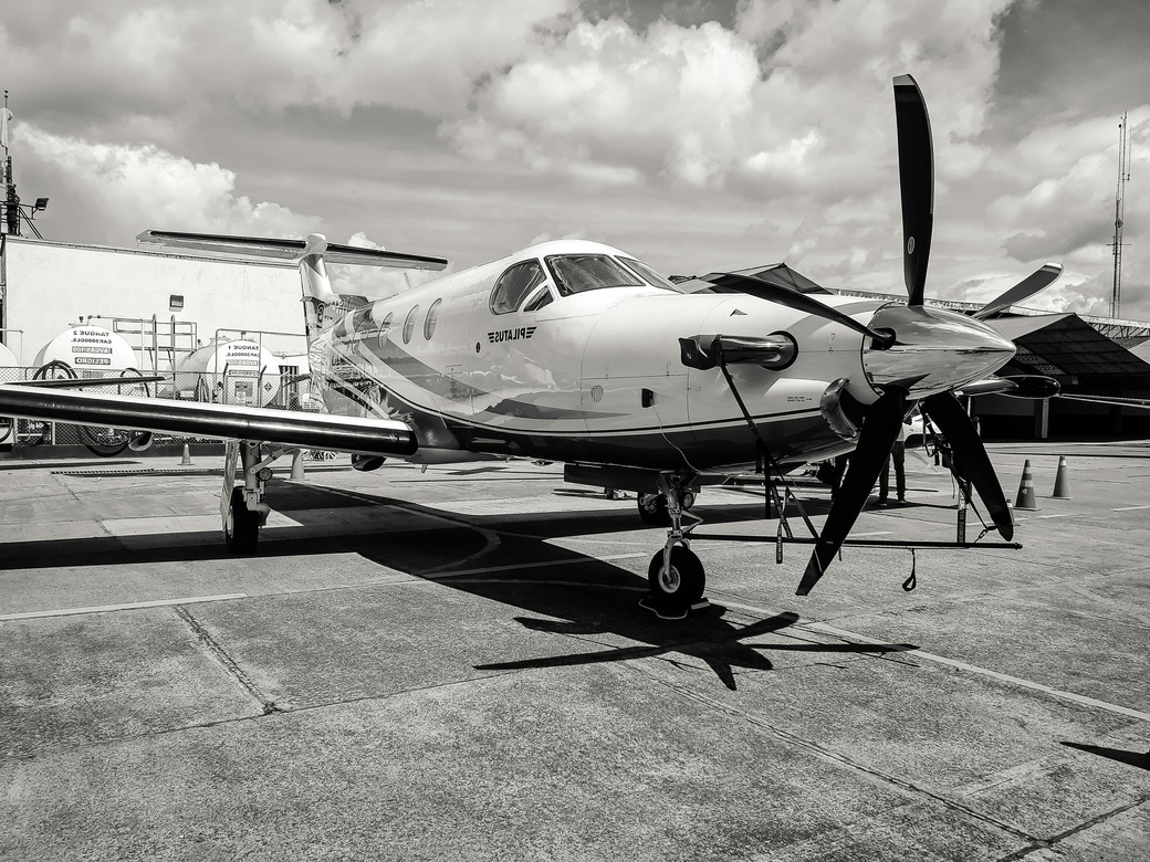 Turboprop airplane on tarmac, facing forward with propellor blades visible. Cloudy sky backdrop. Jet Mentis Partners