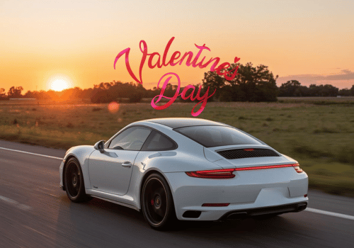 White sports car driving at sunset with Valentine’s Day text in the sky.