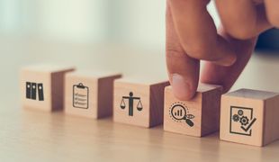 Une personne empile des blocs de bois avec des icônes dessus.