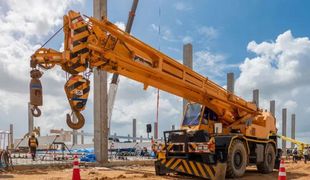 Une grande grue jaune est assise au sommet d'un chantier de construction.