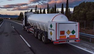 Un camion-citerne roule sur une autoroute au coucher du soleil.