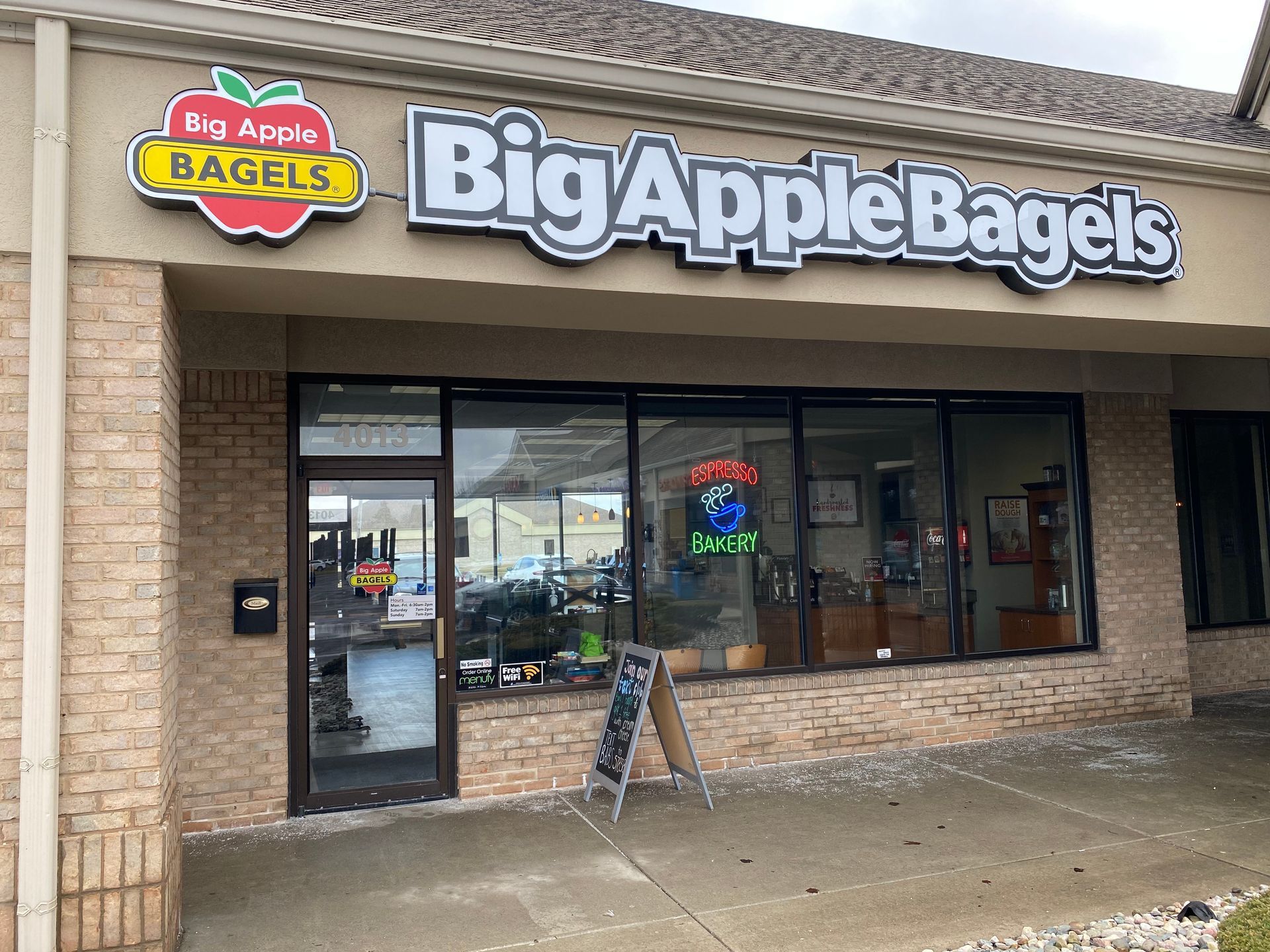 A big apple bagels restaurant is located in a brick building.